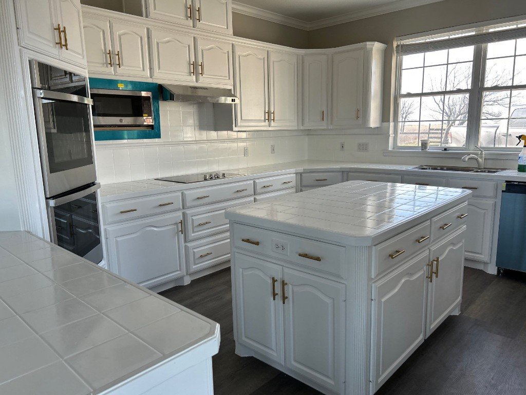 Renovated kitchen with white cabinetry, central island, and stainless appliances